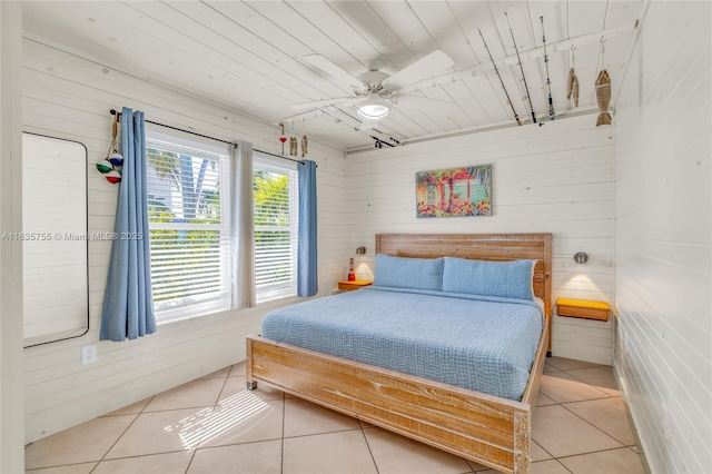 bedroom with light tile patterned floors, rail lighting, wood ceiling, ceiling fan, and wood walls