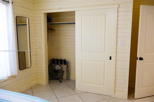 bedroom featuring light tile patterned flooring and wood walls