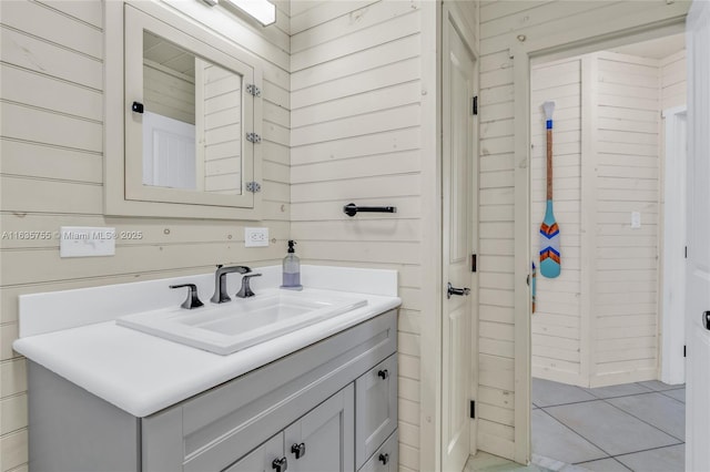 bathroom with tile patterned flooring, vanity, and wooden walls