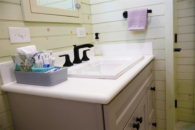 bathroom with vanity, wood walls, and toilet