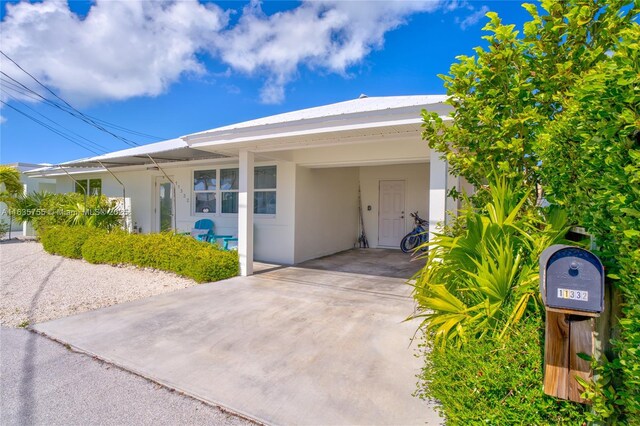 view of front of house featuring a carport, concrete driveway, and stucco siding