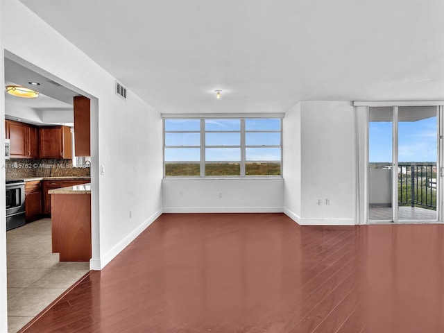 spare room featuring wood finished floors, visible vents, and baseboards