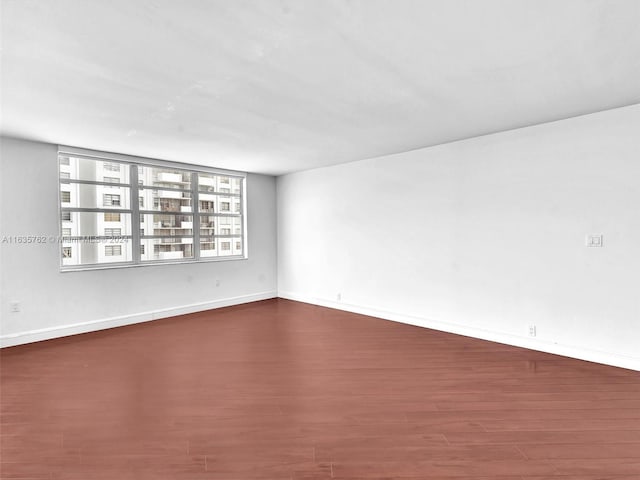 spare room with baseboards and wood finished floors