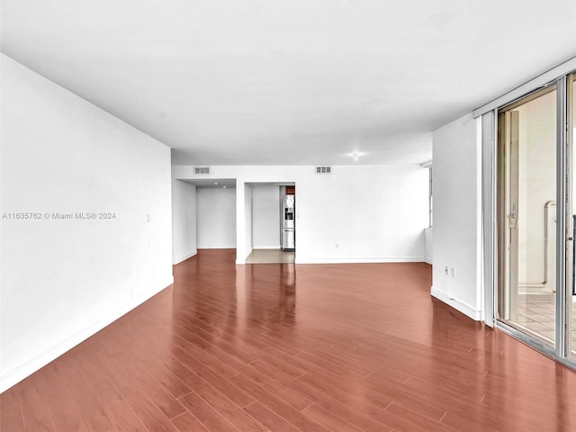 unfurnished room featuring wood finished floors, visible vents, and baseboards