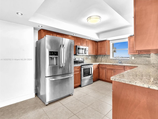 kitchen with tasteful backsplash, appliances with stainless steel finishes, and a tray ceiling