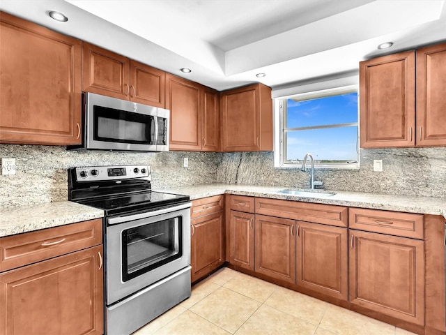 kitchen featuring appliances with stainless steel finishes, brown cabinets, and a sink