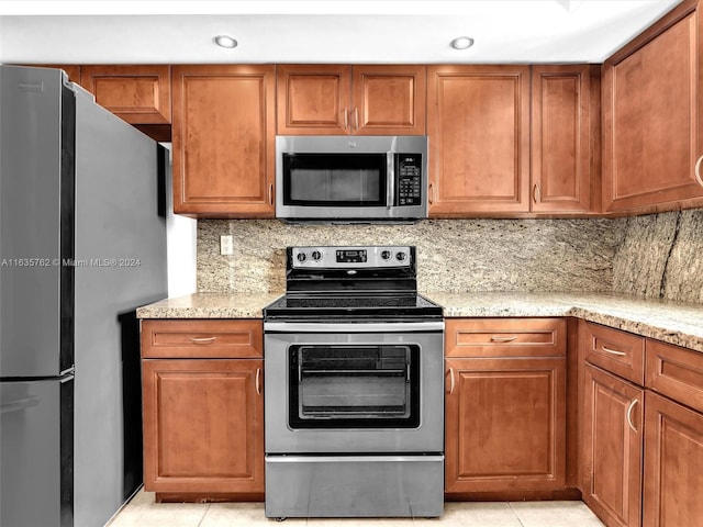 kitchen with appliances with stainless steel finishes, brown cabinetry, and light stone counters