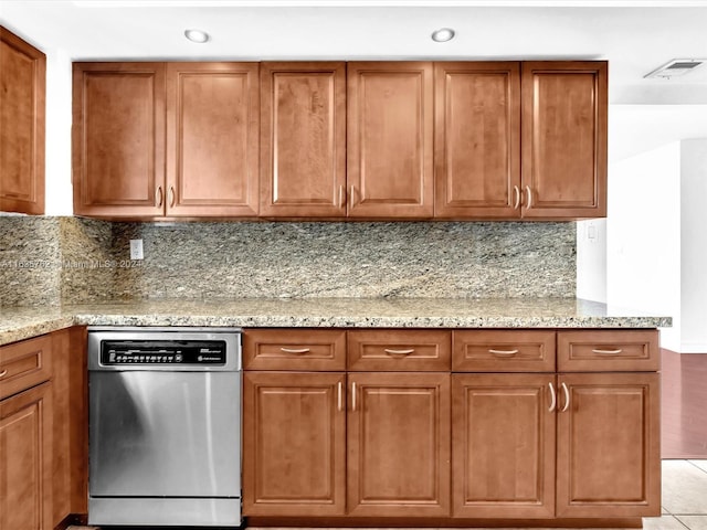 kitchen with brown cabinets, dishwasher, decorative backsplash, and light stone countertops