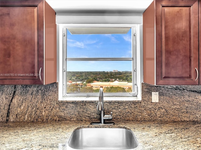 kitchen with tasteful backsplash, a sink, and light stone countertops