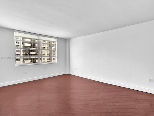 unfurnished room featuring baseboards and dark wood finished floors