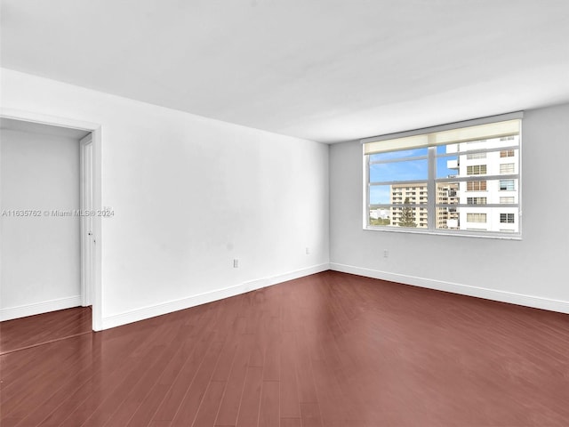 spare room featuring baseboards and dark wood-style flooring