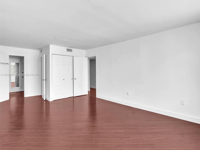 unfurnished bedroom featuring a closet, wood finished floors, visible vents, and baseboards