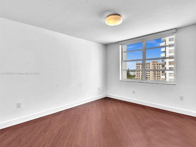 unfurnished room with dark wood-style floors and baseboards