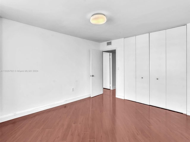 unfurnished bedroom featuring a closet, visible vents, baseboards, and wood finished floors