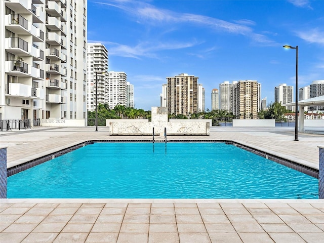 community pool with a city view and a patio