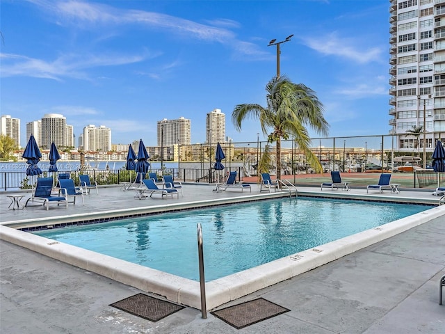 pool featuring a view of city, a patio area, and fence