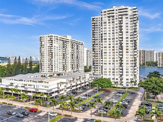 view of property featuring a water view, uncovered parking, and a city view