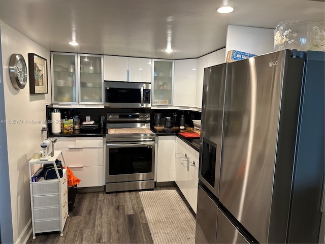 kitchen with appliances with stainless steel finishes, dark hardwood / wood-style floors, and white cabinetry