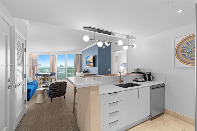 kitchen featuring a breakfast bar, sink, kitchen peninsula, white cabinetry, and dishwasher