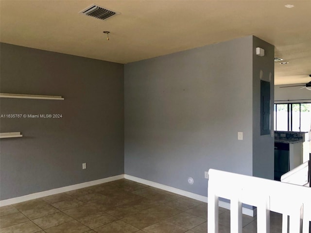 tiled spare room with electric panel and ceiling fan