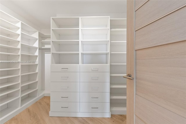 walk in closet with light wood finished floors