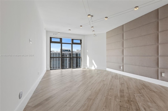 empty room with light wood finished floors, a view of city, and baseboards