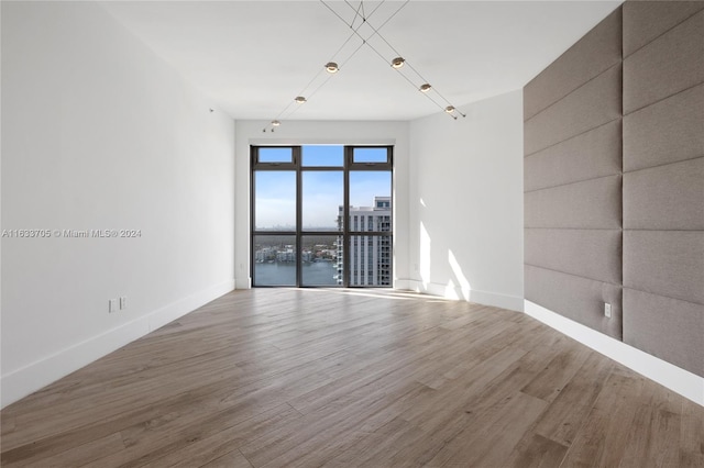 unfurnished room with a water view, baseboards, and wood finished floors