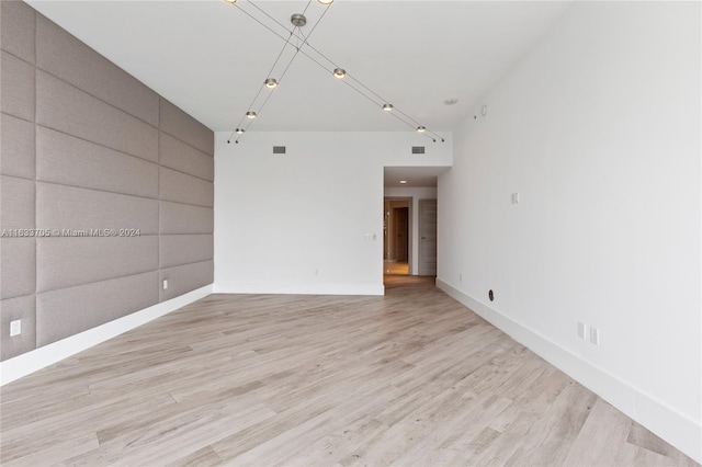 unfurnished room featuring light wood-type flooring, visible vents, and baseboards