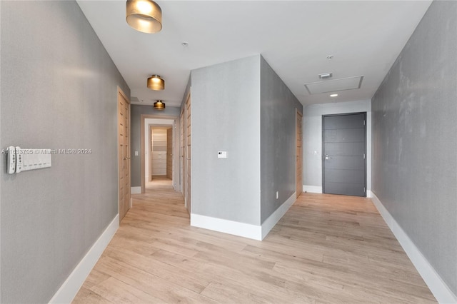 hall with attic access, light wood-style flooring, and baseboards