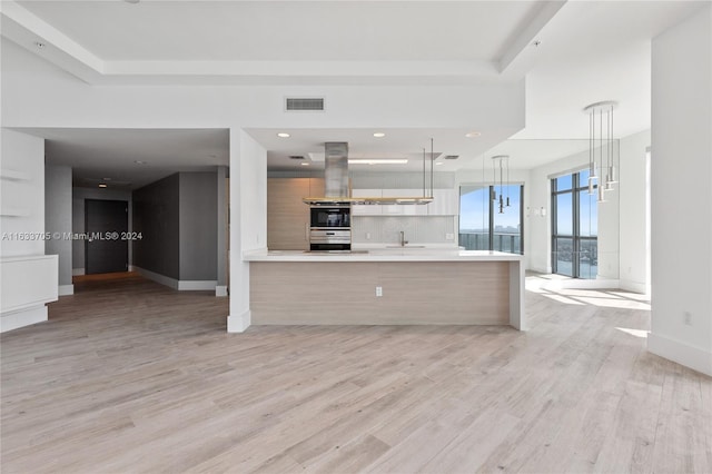 kitchen with visible vents, modern cabinets, decorative light fixtures, light countertops, and light wood-type flooring