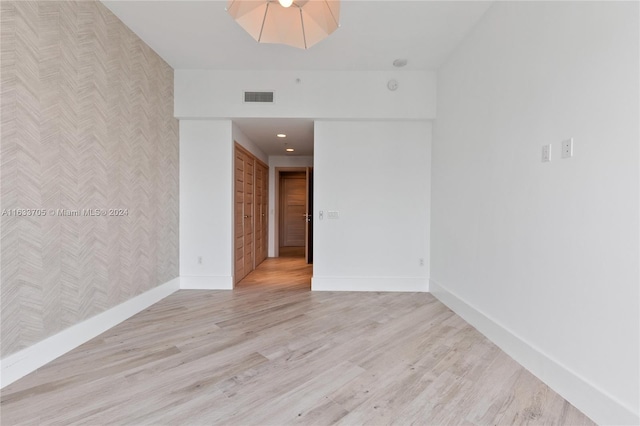 spare room featuring wallpapered walls, baseboards, an accent wall, and visible vents