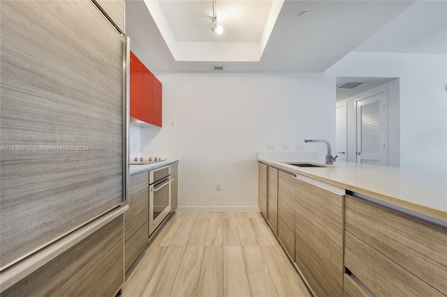 kitchen featuring black electric stovetop, oven, a sink, visible vents, and a tray ceiling