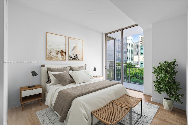 bedroom featuring access to exterior, light wood-type flooring, and a wall of windows