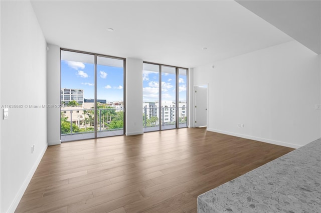 empty room with a wall of windows and dark wood-type flooring