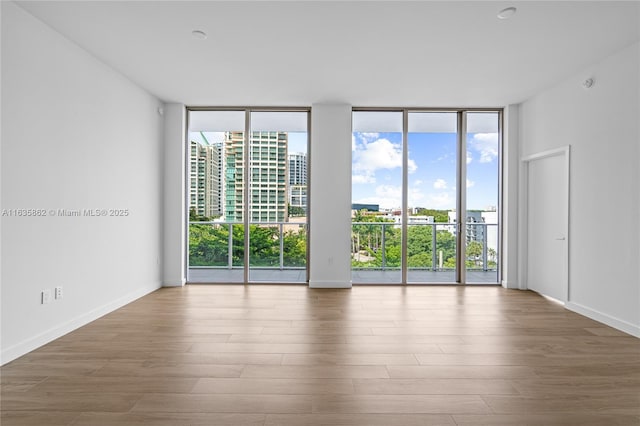 spare room with hardwood / wood-style flooring, plenty of natural light, and a wall of windows