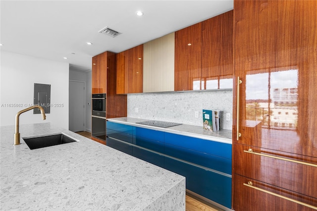 kitchen featuring light stone countertops, sink, electric panel, decorative backsplash, and black appliances