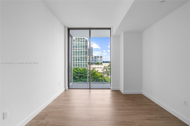 spare room with floor to ceiling windows and light hardwood / wood-style flooring