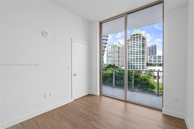 empty room featuring expansive windows and light hardwood / wood-style floors