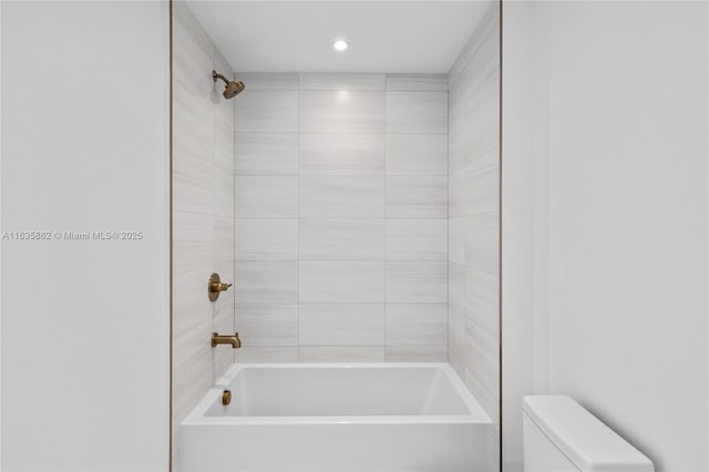 bathroom with toilet and tiled shower / bath