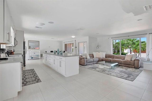 kitchen with white cabinets, stainless steel dishwasher, light tile patterned floors, backsplash, and sink