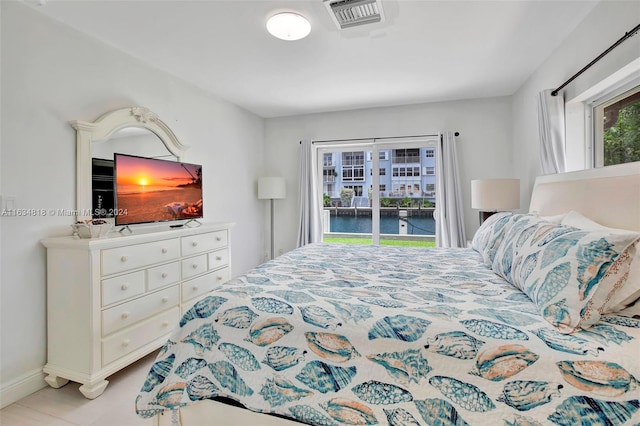 bedroom featuring light tile patterned flooring, a water view, and multiple windows