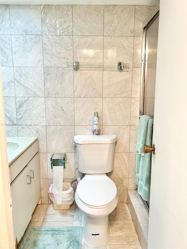 bathroom with vanity, toilet, walk in shower, and tile walls