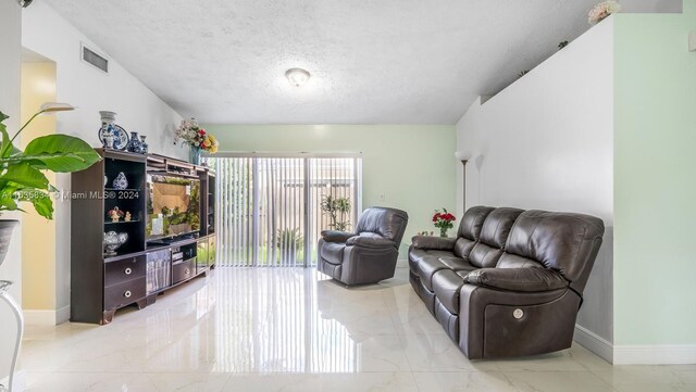 living area featuring light tile patterned flooring and a textured ceiling