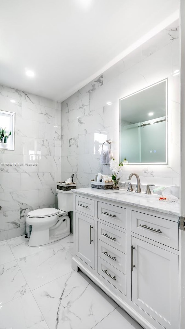 bathroom with vanity, toilet, tile patterned flooring, and tile walls