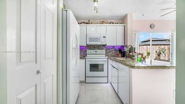 kitchen with white appliances, white cabinets, backsplash, light tile patterned floors, and a textured ceiling