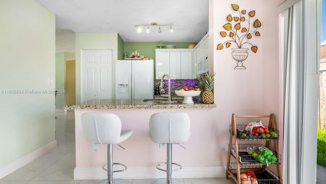 kitchen with white cabinets, white appliances, sink, kitchen peninsula, and track lighting