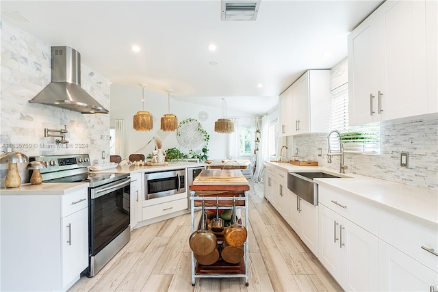 kitchen with wall chimney range hood, appliances with stainless steel finishes, a wealth of natural light, and sink