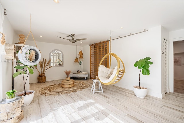 sitting room with ceiling fan and light wood-type flooring