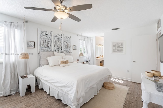 bedroom with ceiling fan, a textured ceiling, and light hardwood / wood-style floors