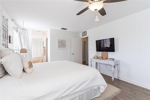 bedroom with a textured ceiling, dark wood-type flooring, and ceiling fan